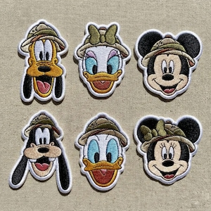 Puede incluir: Seis parches bordados con los personajes de Disney Pluto, Daisy Duck, Mickey Mouse, Goofy, Donald Duck y Minnie Mouse. Cada personaje lleva un sombrero de safari. Los parches están delineados en blanco.