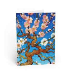 May include: A greeting card displaying a painting of a flowering tree with pink and white blossoms set against a blue backdrop. The artwork has a textured, brushstroke style, with a focus on the tree's branches and flowers.