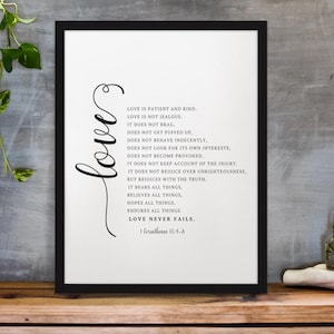 Puede incluir: Impresión enmarcada en negro con la palabra "love" en escritura cursiva y el texto "Love is Patient and Kind" sobre un fondo blanco. La impresión se muestra sobre una superficie de madera.