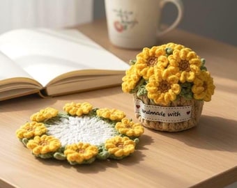 May include: Handmade crochet sunflower coaster and decorative flower pot. The coaster is white with yellow flower accents. The flower pot is a small basket filled with yellow crochet sunflowers. The pot has a small tag that says "handmade with".
