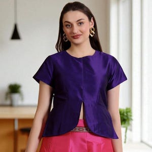 May include: A vibrant purple top with short sleeves and a split front, worn with a bright pink skirt. The top features a rounded neckline and a fitted design. This outfit is suitable for formal or semi-formal events.