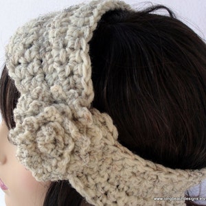 May include: A crocheted headband with a large flower detail in a cream color. The headband is made with a chunky yarn and has a simple, elegant design.