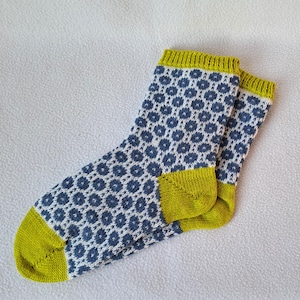 May include: A pair of socks with a white and blue geometric pattern and a yellow cuff.