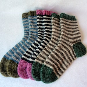 K&ouml;nnte beinhalten: Drei Paar gestreifte Stricksocken in Blau, Schwarz und Braun mit gr&uuml;nen, rosa und braunen Fersen und Zehen.