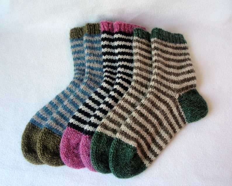 K&ouml;nnte beinhalten: Drei Paar gestreifte Stricksocken in Blau, Schwarz und Braun mit gr&uuml;nen, rosa und braunen Fersen und Zehen.