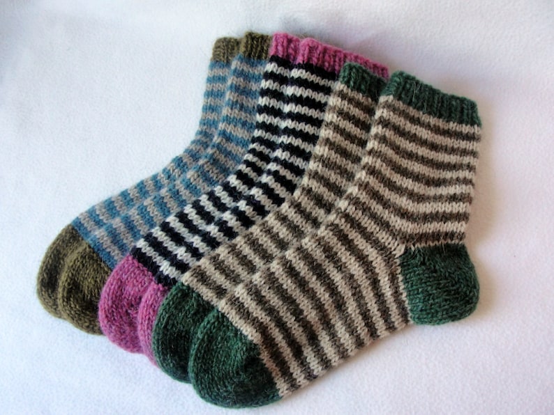 K&ouml;nnte beinhalten: Vier Paar gestreifte Stricksocken in verschiedenen Farben, darunter Gr&uuml;n, Braun, Schwarz, Wei&szlig;, Blau und Pink.