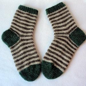 K&ouml;nnte beinhalten: Ein Paar gestreifte Socken mit braunen und wei&szlig;en Streifen und gr&uuml;nen Zehen und Fersen.