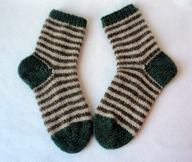 K&ouml;nnte beinhalten: Ein Paar gestreifte Socken mit braunen und wei&szlig;en Streifen und gr&uuml;nen Zehen und Fersen.