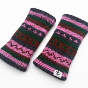 May include: A pair of knitted fingerless gloves in shades of pink, green, brown, and gray. The gloves feature a geometric pattern and a small white tag with a logo. The gloves are designed to keep hands warm.