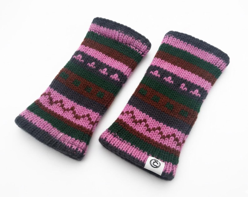 May include: A pair of knitted fingerless gloves in shades of pink, green, brown, and gray. The gloves feature a geometric pattern and a small white tag with a logo. The gloves are designed to keep hands warm.