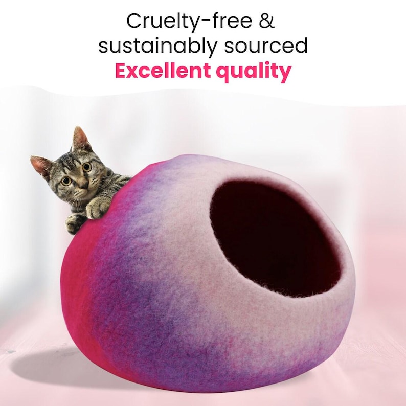 May include: A cat peeks out of a felted cat cave. The cave is a gradient of pink, purple, and white. The text at the top reads "Cruelty-free & sustainably sourced Excellent quality."