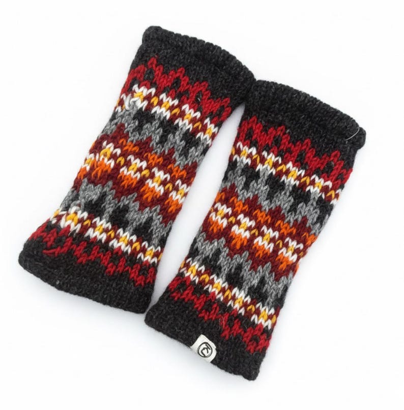 May include: A pair of knitted fingerless gloves in a fair isle pattern. The gloves feature a black cuff and a design of red, orange, gray, white, and yellow geometric shapes. A small white tag with a logo is visible on one glove.