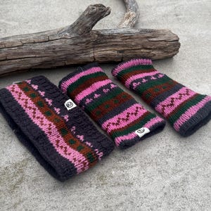 May include: A dark gray knitted headband and two matching wrist warmers. The accessories feature a pink, green, and brown geometric pattern. The items are made of a thick, textured yarn and are displayed on a concrete surface.