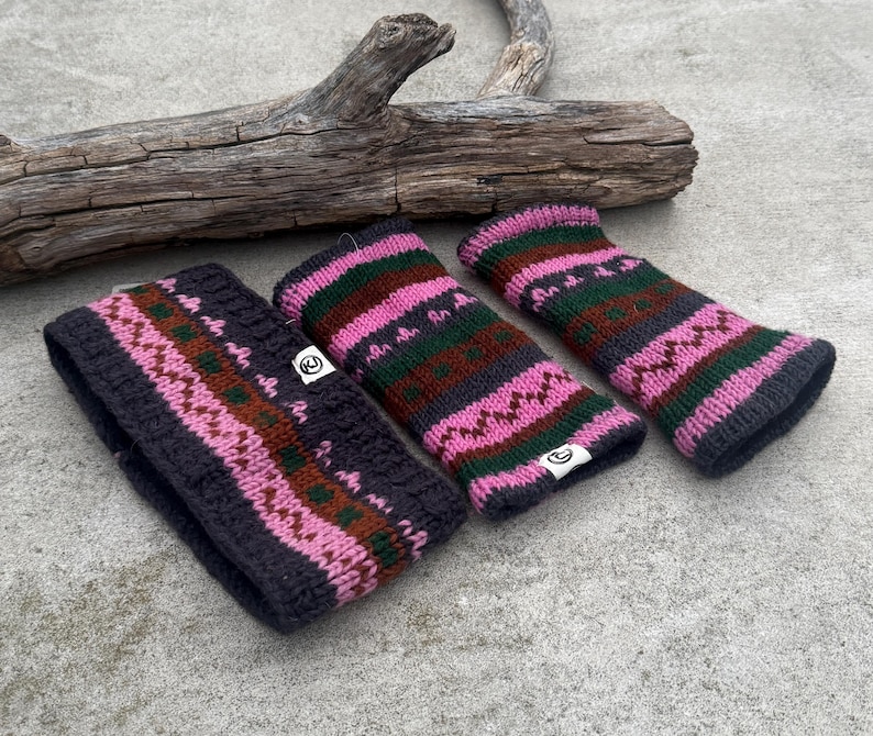May include: A dark gray knitted headband and two matching wrist warmers. The accessories feature a pink, green, and brown geometric pattern. The items are made of a thick, textured yarn and are displayed on a concrete surface.