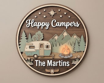 May include: A round wooden sign with the words "Happy Campers" in white script. The sign features a camping scene with a trailer, mountains, trees, a campfire, and the text "The Martins". Decorative stars and a compass rose are at the top.