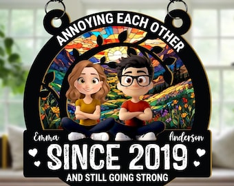 May include: Black decorative sign with the text "ANNOYING EACH OTHER" and "SINCE 2019 AND STILL GOING STRONG". The sign features cartoon figures of a couple and a stained-glass background.