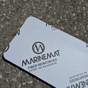 May include: A white rectangular MarineMat product with rounded corners. The product features the MarineMat logo, the words "FIBER REINFORCED", and patent information in black text. The product is on a textured gray surface.
