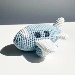 May include: A white ceramic mug with a black handle and the text "But First, Coffee" in a bold, black font. The mug is set against a blurred background, suggesting a cosy setting.