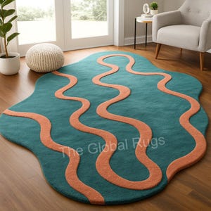 May include: Teal-colored area rug with an organic shape and wavy, coral-colored lines. The rug is on a hardwood floor, and the text "The Global Rugs" is visible on the rug.