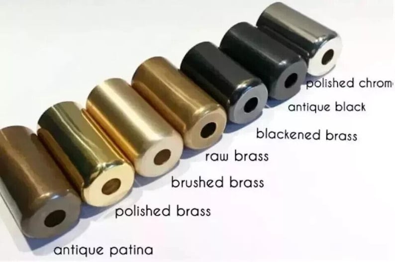 May include: A collection of cylindrical metal objects in various finishes, including polished chrome, antique black, and polished brass. The image displays the names of each finish. The objects are arranged in a row against a white background.