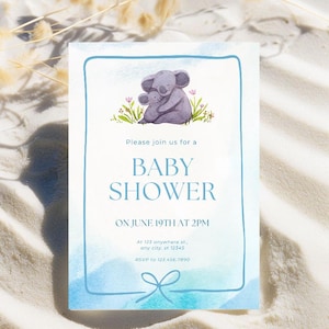 May include: Baby shower invitation with a watercolour design. The invitation features a grey koala and baby koala illustration, with the text "BABY SHOWER" and event details in blue. The invitation is framed with a blue border.