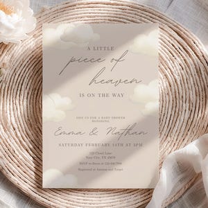 May include: A baby shower invitation with the text "A little piece of heaven is on the way." The invitation is light beige with cloud illustrations and floral accents. The invitation is for Emma & Nathan, Saturday, February 14th at 3 PM.
