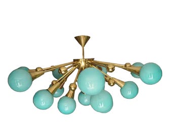 May include: A mid-century modern chandelier with a brass finish and multiple light blue globe-shaped bulbs. The fixture has a starburst design, with arms extending from a central point. The bulbs are evenly spaced.
