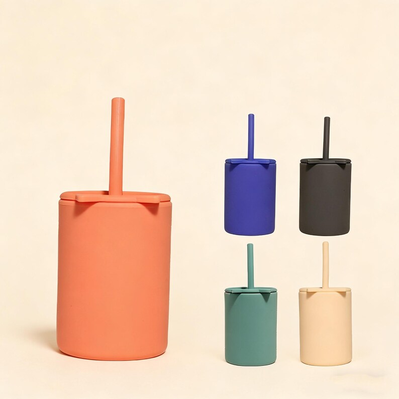 May include: A collection of colorful silicone cups with lids and straws. The cups are in shades of coral, blue, black, teal, and beige. The design is simple and modern, suitable for children's use.