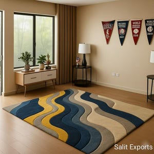 Op de afbeelding: Een groot, rechthoekig vloerkleed met een golvend ontwerp in tinten blauw, geel en beige. Het vloerkleed ligt op een houten vloer in een kamer met een raam, gordijnen en honkbalvaantjes aan de muur.