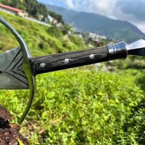 May include: A metal sword featuring a polished steel blade with engraved chevron details, a curved crossguard, and a dark wood handle secured with three silver rivets, finished with a pointed metal pommel at the end of the grip.