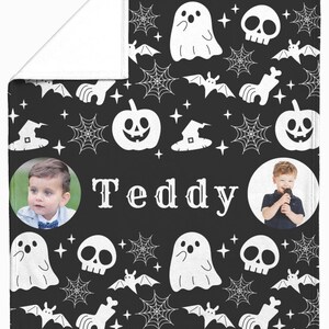 May include: Black Halloween-themed blanket with white illustrations of ghosts, bats, spiderwebs, witch hats, and pumpkins. The name "Teddy" is printed in the center, with two circular photos of a child on either side.