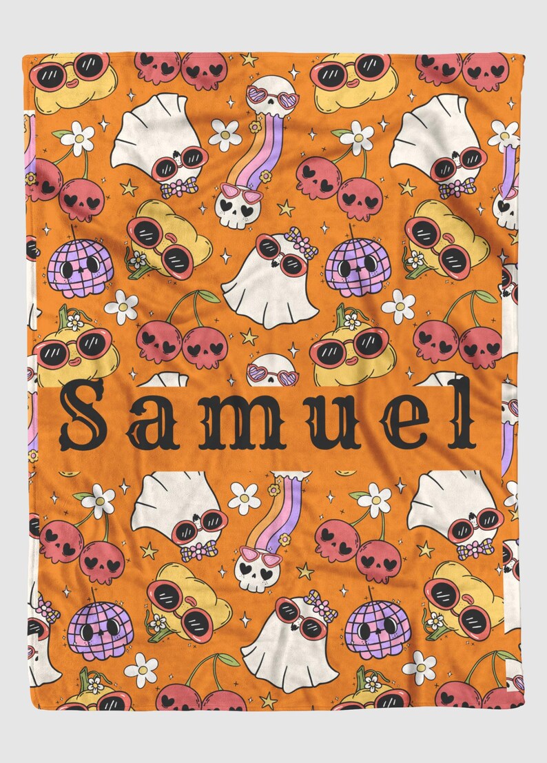 May include: Orange blanket with a repeating pattern of cartoon skulls, cherries, ghosts, and disco balls, all wearing sunglasses. The word "SAMUEL" is printed in large black letters across the center.