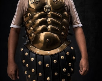 May include: A polished brass Roman-style cuirass with a lion emblem and decorative accents. The armor features a segmented design and is paired with a black leather skirt adorned with gold studs. The overall aesthetic is historical and detailed.