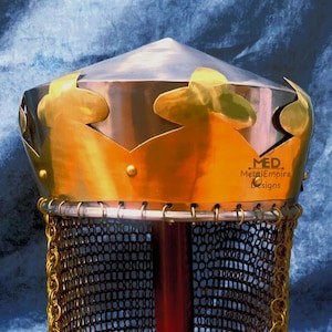 Könnte beinhalten: Nahaufnahme eines mittelalterlichen Helms mit goldenem Kronenmuster. Der Helm hat eine silberne Oberseite und eine goldfarbene Krone mit dekorativen Ausschnitten. Der untere Teil zeigt Kettenhemden und den Text "MED. MetalEmpire Designs."