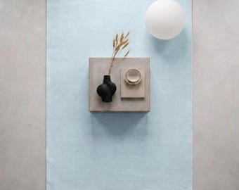 Tapis bleu clair tufté à la main, style minimaliste et moderne, aux teintes pastel douces, pièce maîtresse de la décoration intérieure.