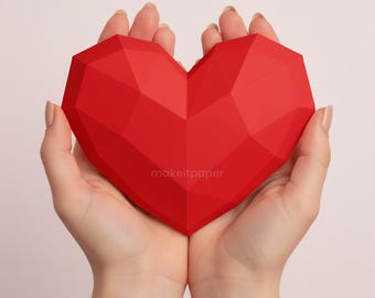 Könnte beinhalten: Ein facettiertes, leuchtend rotes herzförmiges Objekt wird in geformten Händen gehalten. Das Herz hat ein geometrisches Design und der Text "makeitpaper" ist unten rechts aufgedruckt. Der Hintergrund ist eine weiche, neutrale Farbe.