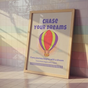 May include: A framed poster with the words "CHASE YOUR DREAMS" in purple. The poster features a colorful hot air balloon illustration. Below the balloon are the words "Every journey begins with a dream" and "Every dream begins with a spark".