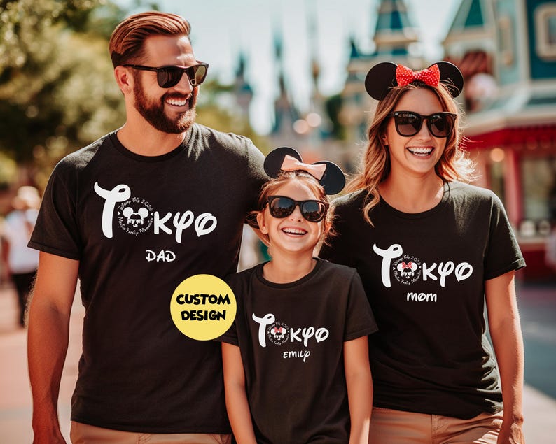May include: Black t-shirts with a white "Tokyo" design and Mickey Mouse graphic. The shirts are labeled "Dad," "Mom," and "Emily." The family is wearing sunglasses and Mickey Mouse ears. A yellow "Custom Design" sticker is visible.