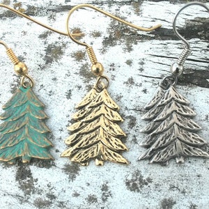 May include: Three pairs of earrings featuring a stylized pine tree design. The earrings are made of metal and come in three finishes: gold, silver, and green.