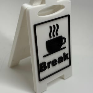 Op de afbeelding: Wit A-frame bord met een zwarte rand. Het bord toont een zwarte koffiekop met stoom en het woord "Break" in het zwart. Het bord is ontworpen om zelfstandig te staan.