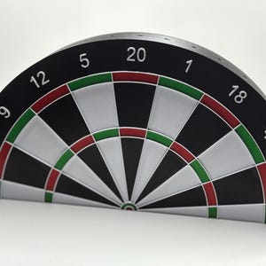 Könnte beinhalten: Ein halbkreisförmiges Dartboard mit schwarzem Hintergrund, weißen Abschnitten und roten und grünen Ringen. Die Zahlen sind weiß am Rand aufgedruckt. Das Dartboard ist für das Dartspiel konzipiert.