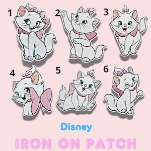 Puede incluir: Seis parches termoadhesivos de gato blanco con lazos y collares rosas, cada uno en una pose diferente. La palabra "Disney" está en azul y "IRON ON PATCH" en rosa, sobre un fondo rosa claro.