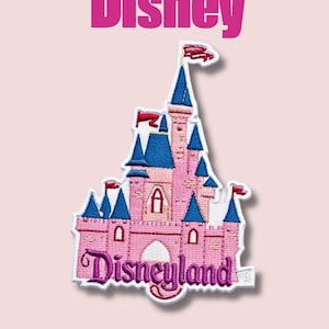 Puede incluir: Parche bordado con un castillo rosa con torretas azules y banderas rojas. El parche tiene la palabra "Disney" encima del castillo y "Disneyland" debajo, ambas en una fuente púrpura. El parche está sobre un fondo rosa claro.