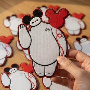 Pode incluir: Patches bordados em branco e preto com um personagem de desenho animado com um balão vermelho. O personagem tem um corpo branco, orelhas pretas e um contorno preto. O balão vermelho tem a forma das orelhas do Mickey Mouse.