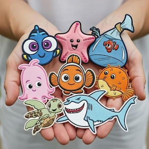 Puede incluir: Una colección de parches bordados coloridos con personajes de la película animada "Buscando a Nemo". Los parches incluyen a Dory, Nemo, una estrella de mar, un pez globo, un tiburón, una tortuga, un pulpo y un pez en una bolsa.