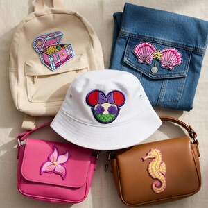 May include: An assortment of accessories featuring embroidered patches. Includes a beige backpack with a treasure chest, a denim jacket with seashell patches, a white bucket hat with a Minnie Mouse design, a pink purse with a flower, and a brown purse with a seahorse.