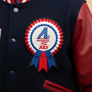 May include: A navy blue varsity jacket with red leather sleeves and a white, red, and blue striped collar. The jacket features a circular patch with "4th of July" text and a ribbon design.
