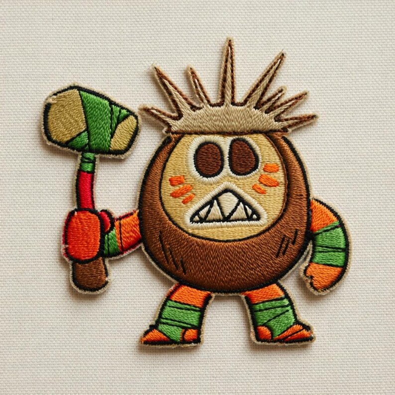 May include: Embroidered patch featuring a cartoon character with a coconut-like head, spiky crown, and orange accents. The character holds a hammer with green and brown details. The patch has a white background.