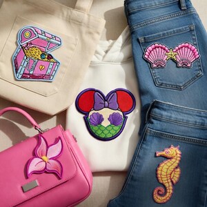 May include: A white ceramic mug with a black handle and the text "But First, Coffee" in a black, handwritten-style font. The mug is on a white surface.