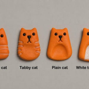 May include: Four orange cat-shaped ornaments with black eyes and noses. The first is a Striped cat with horizontal lines, the second is a Tabby cat with side stripes, the third is a Plain cat, and the fourth is a White tummy cat with a textured white belly.